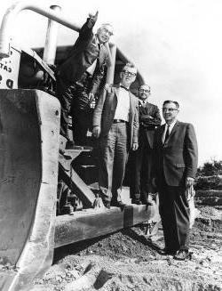 Group of men standing on construction equipment at TCC campus in 1965. Black and white photo.